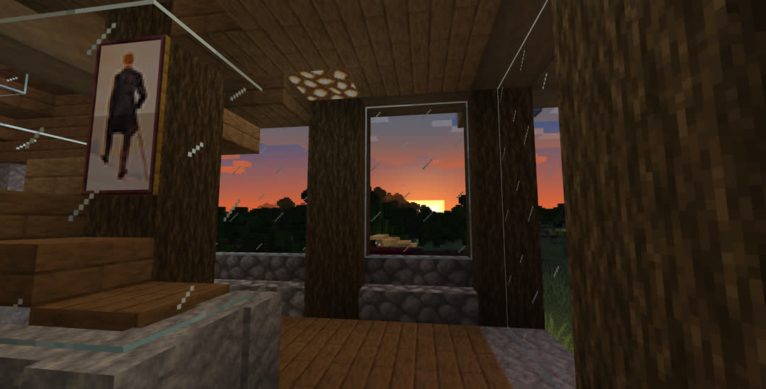 View from the main floor, looking west with the back of the house to the right. Through the windows, the sun is setting behind the forest, almost all of the visible sky in orange.
