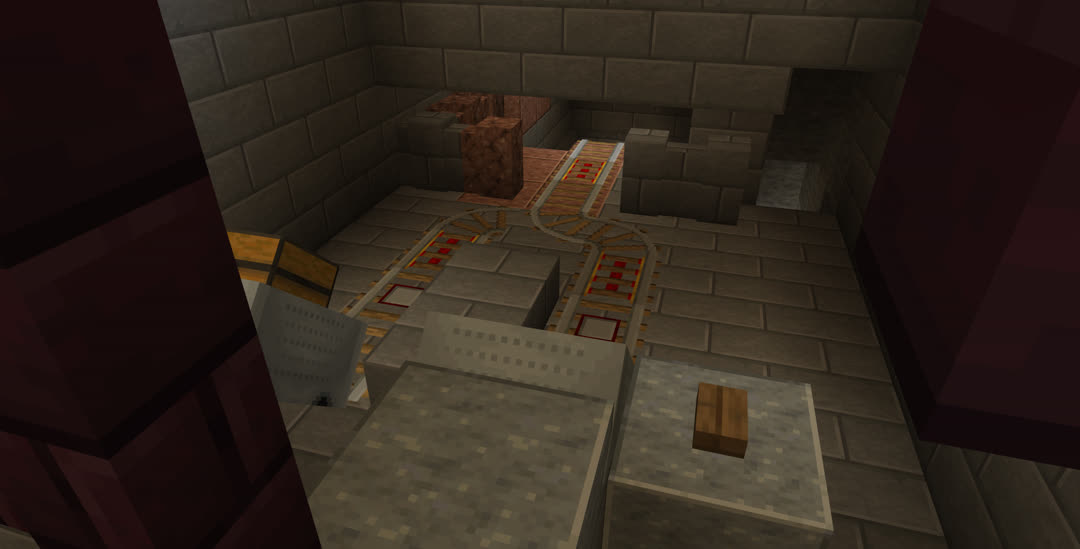 Looking down over a small rail setup in the vault. Minecarts, one with a chest, rest in two separate bays that merge into a single track that disappears down a descending tunnel. There is a separate foot tunnel on the right.